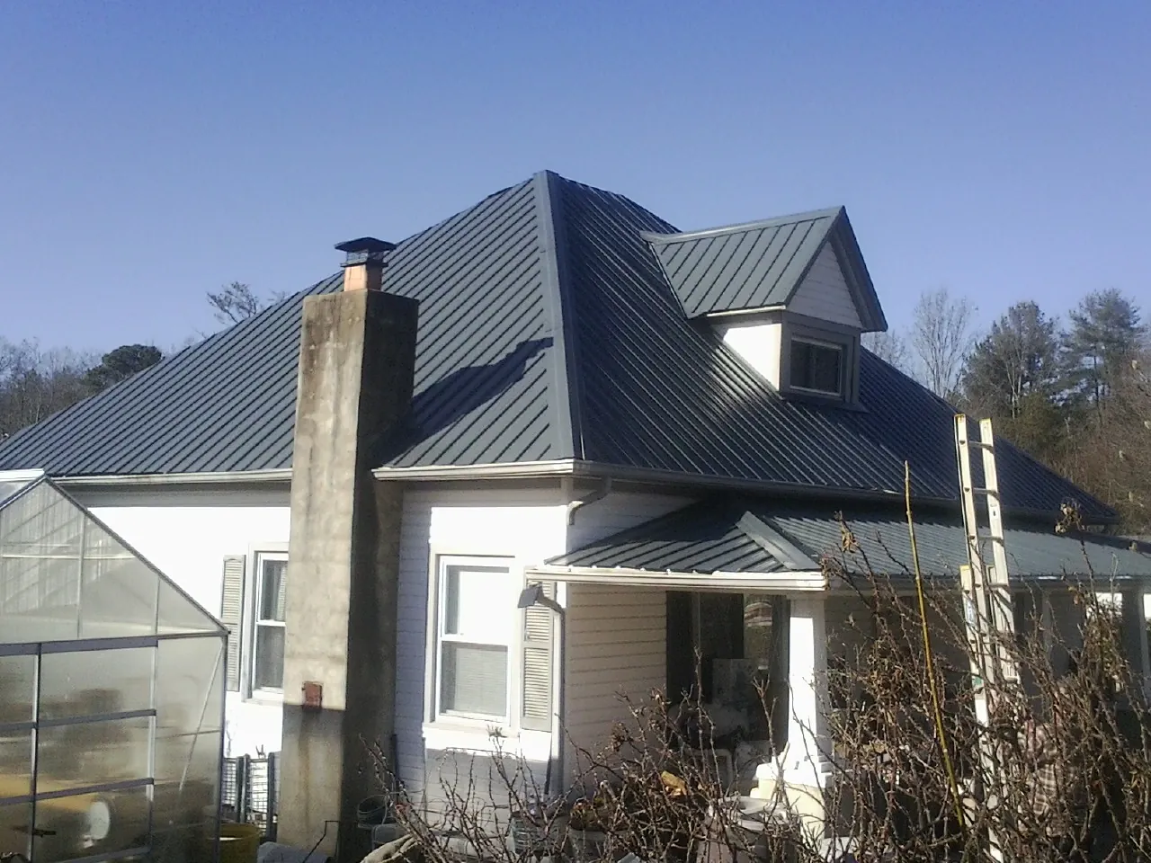 Dark blue standing seam metal roof on a white farmhouse with dormer — Slate & Tile Roof Repair by Roofing Brothers in Rock Stream