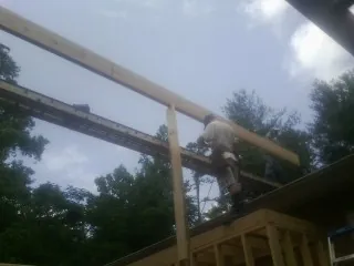 Carpenter setting a ridge beam over a new addition frame — Ice Dam Removal by Roofing Brothers in Rock Stream