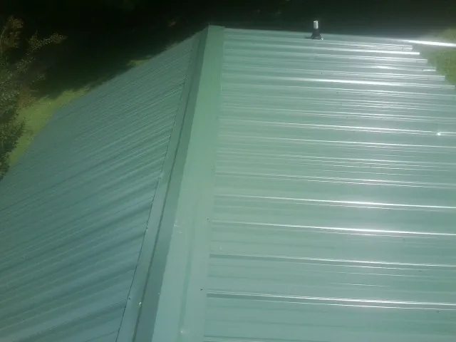 New green metal panels meeting at the ridge of a roof — Flat Roof Repair work by our crew in Rock Stream