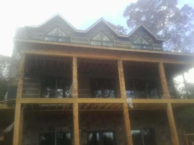 Dormers and porch framing on a large log home under construction — Roof Coating work by our crew in Rock Stream