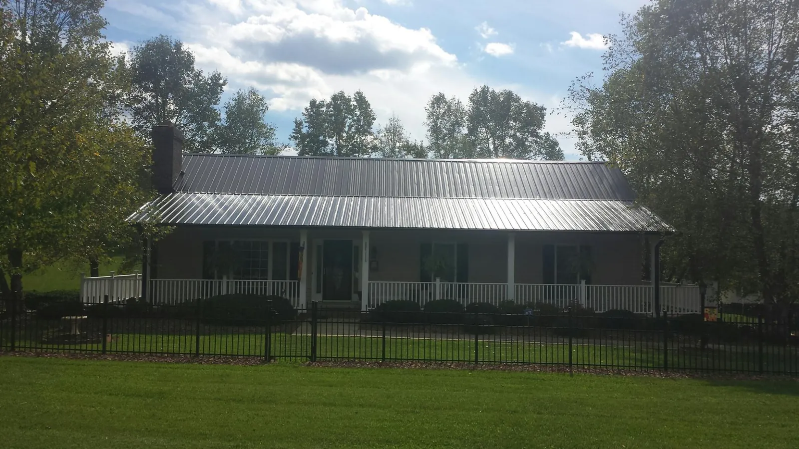 Gray metal roof on a brick ranch with a full width front porch — Gutter Guard Installation work by our crew in Rock Stream
