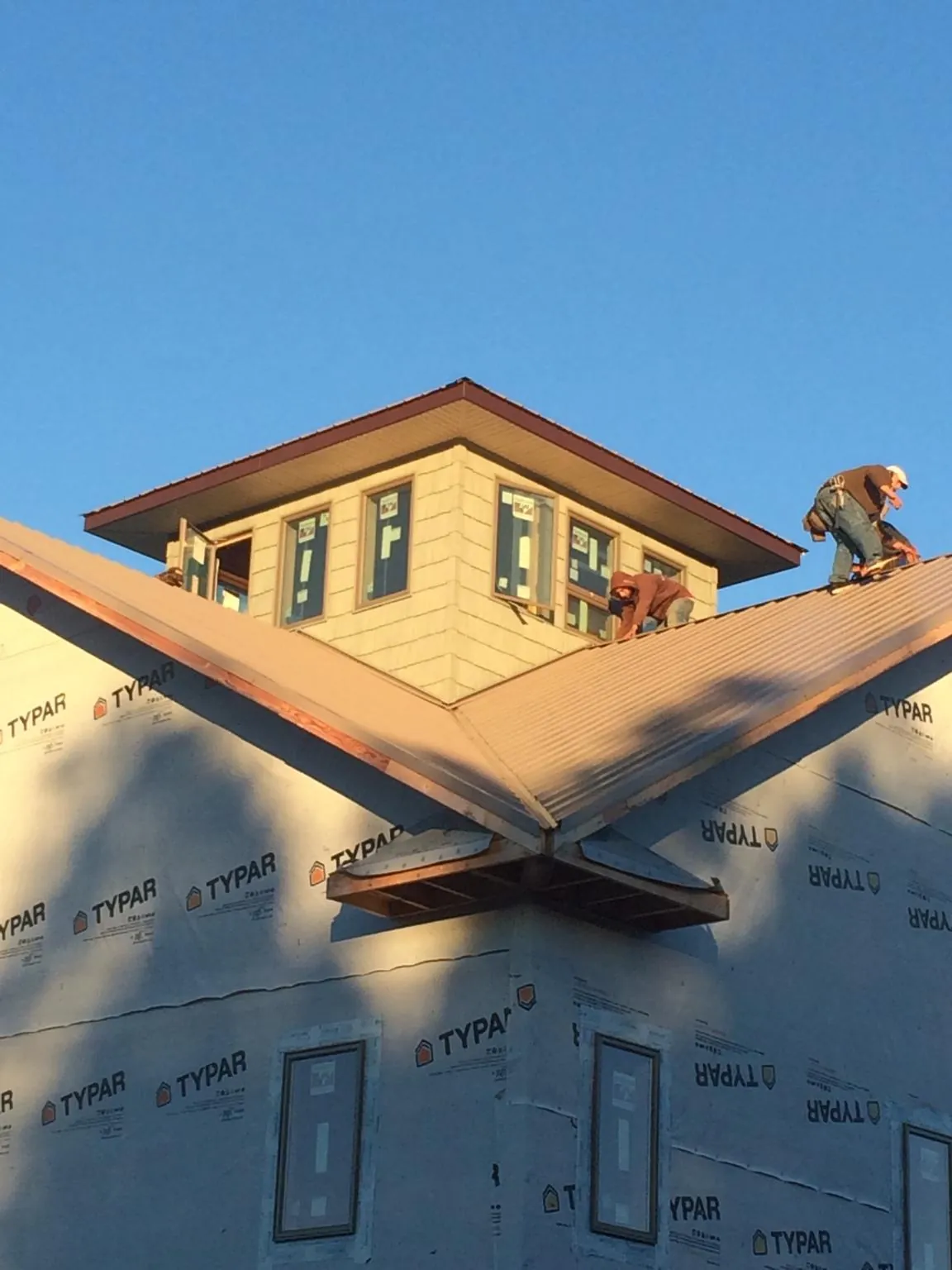 Roofers working around a rooftop cupola on a new metal roof at sunset — Roof Waterproofing in Rock Stream by Roofing Brothers
